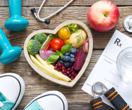 An image shows a heart-shaped tray filled with various fruits and vegetables, accompanied by a medical chart