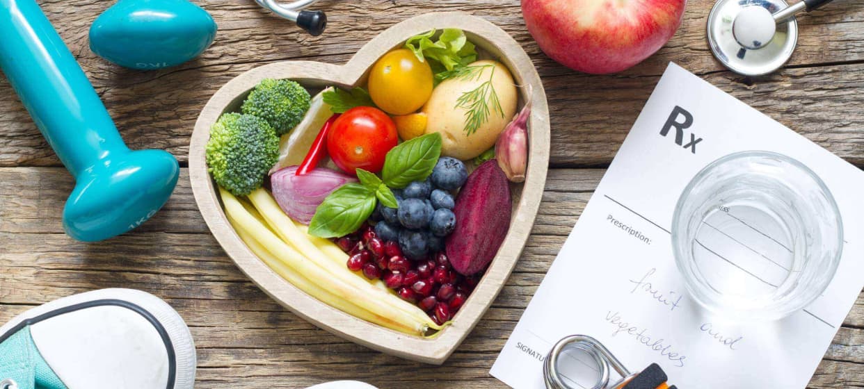 An image shows a heart-shaped tray filled with various fruits and vegetables, accompanied by a medical chart